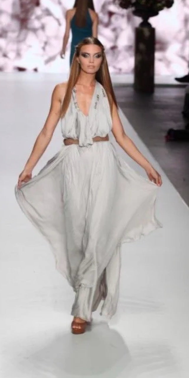 Kim Feenstra op de catwalk in een lichtgrijze jurk